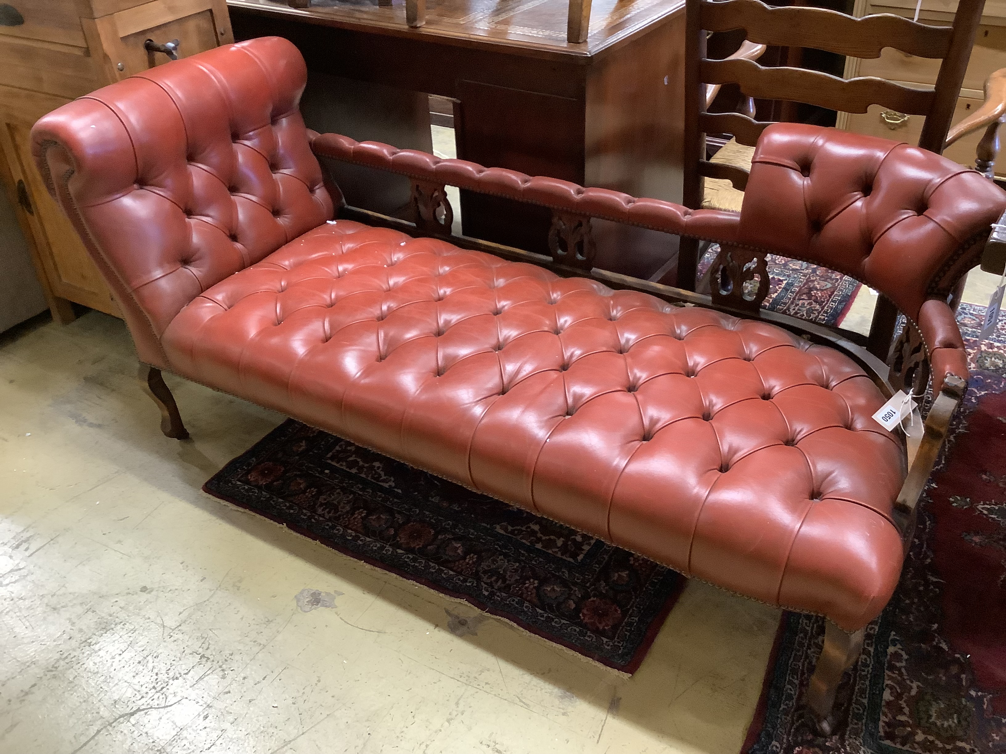 An Edwardian beech two-seater couch upholstered in buttoned burgundy hide on scrolled legs, length 160cm, depth 60cm, height 70cm